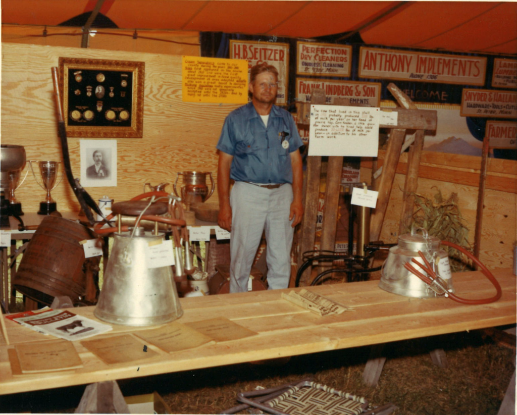 Color photo of a man standing inside a fair booth in 1971
