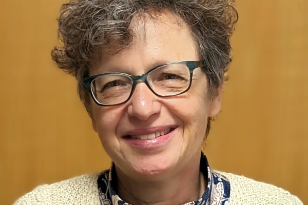 Picture of a woman with short, curly dark hair and glasses.