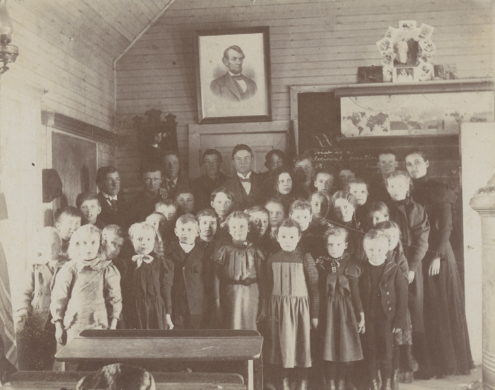 Teacher with students inside a rural schoolhouse.