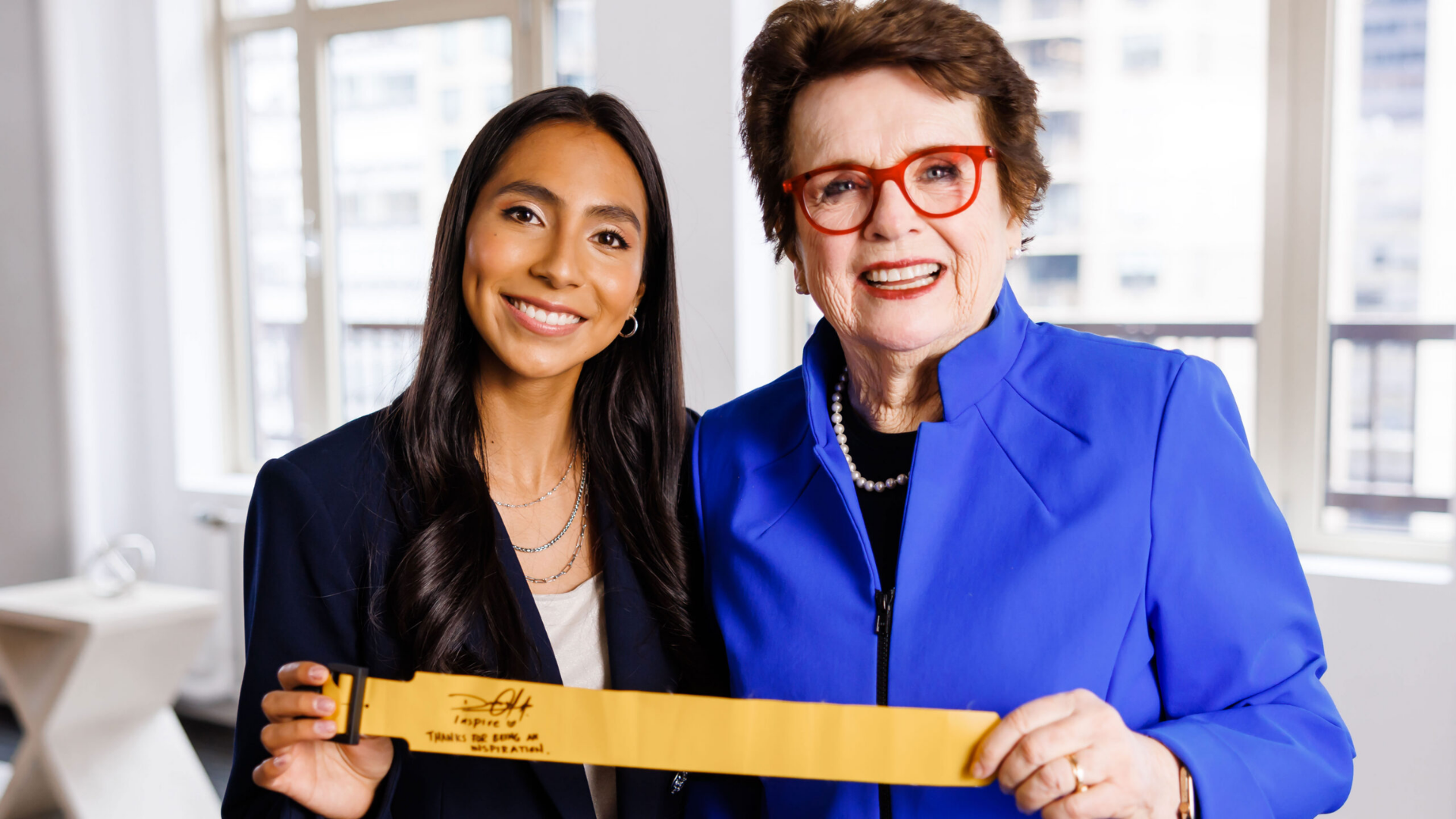 A woman holding a yellow belt with a woman in a blue jacket