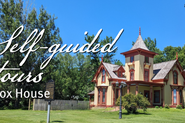 A historic Victorian-style house with ornate trim and tower stands on a lawn with trees under a clear blue sky. White text reads: "Self-guided tours, Cox House.