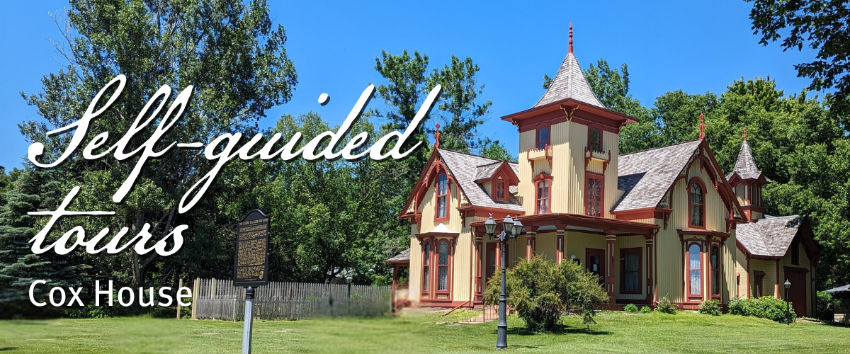 A historic Victorian-style house with a tall tower, decorative trim, and a sign in front; text reads "Self-guided tours Cox House" against a blue sky and green lawn backdrop.
